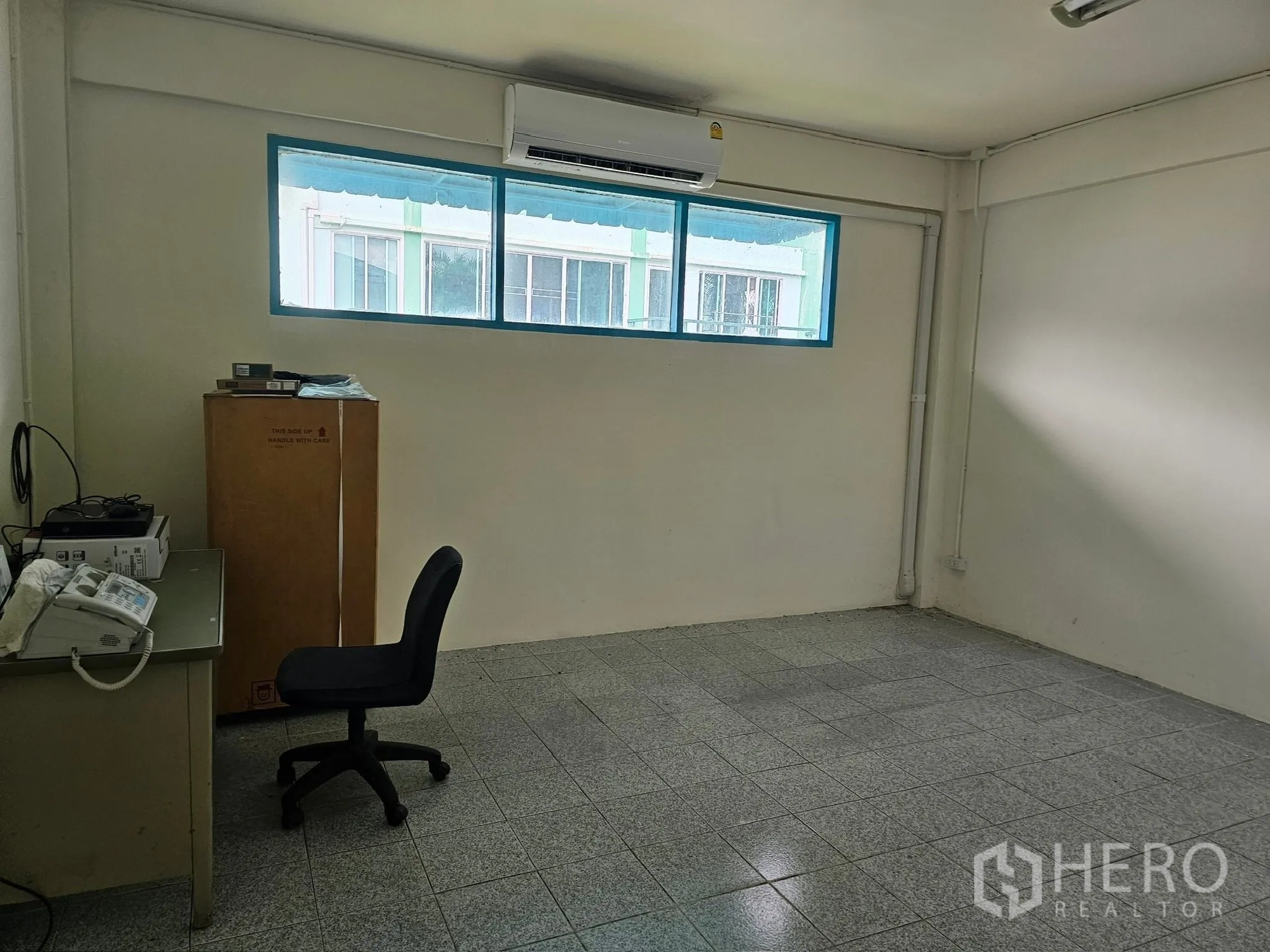 Factory for rent or sale in Mueang Rayong, Rayong - Compact air-conditioned office room with a horizontal window, tiled floor and basic workstation.