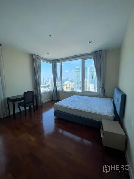 Condominium for rent in Khlong Toei, Bangkok - Master bedroom with corner windows showcasing skyline views, king bed, desk and hardwood floors.