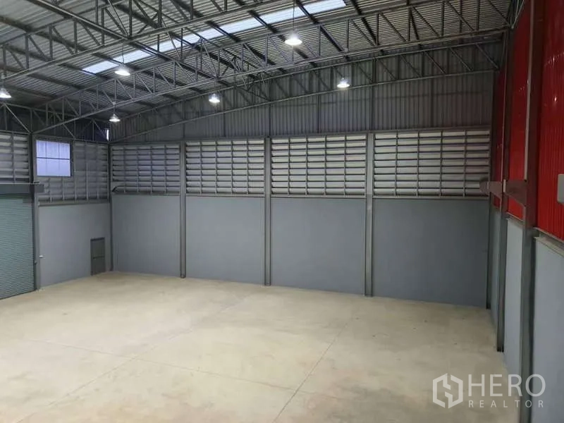 Warehouse for rent in Khlong Luang, Pathum Thani - Spacious warehouse interior with high steel truss roof, skylights, ventilation panels and polished concrete floor.