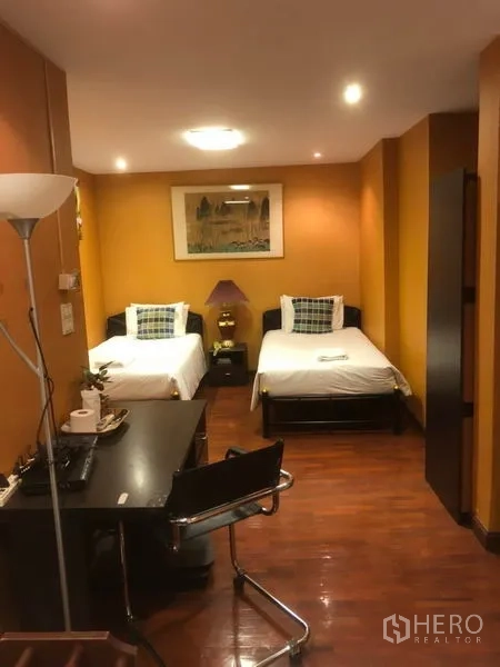 Shophouse for rent in Bang Rak, Bangkok - Room with two single beds, desk and wooden flooring under recessed lights.