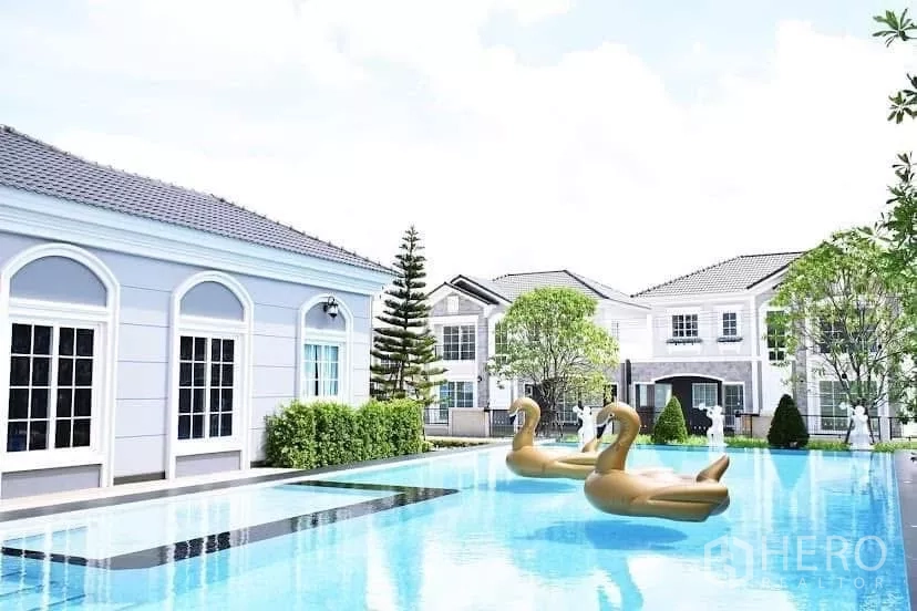 Detached House for rent in Prawet, Bangkok - Residents’ swimming pool beside the clubhouse with inflatable swan floats and neighboring homes.