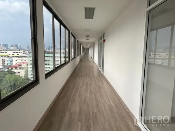 Office Space for rent - Bright corridor with large windows and wood-look floors overlooking the Din Daeng skyline in a Bangkok office building
