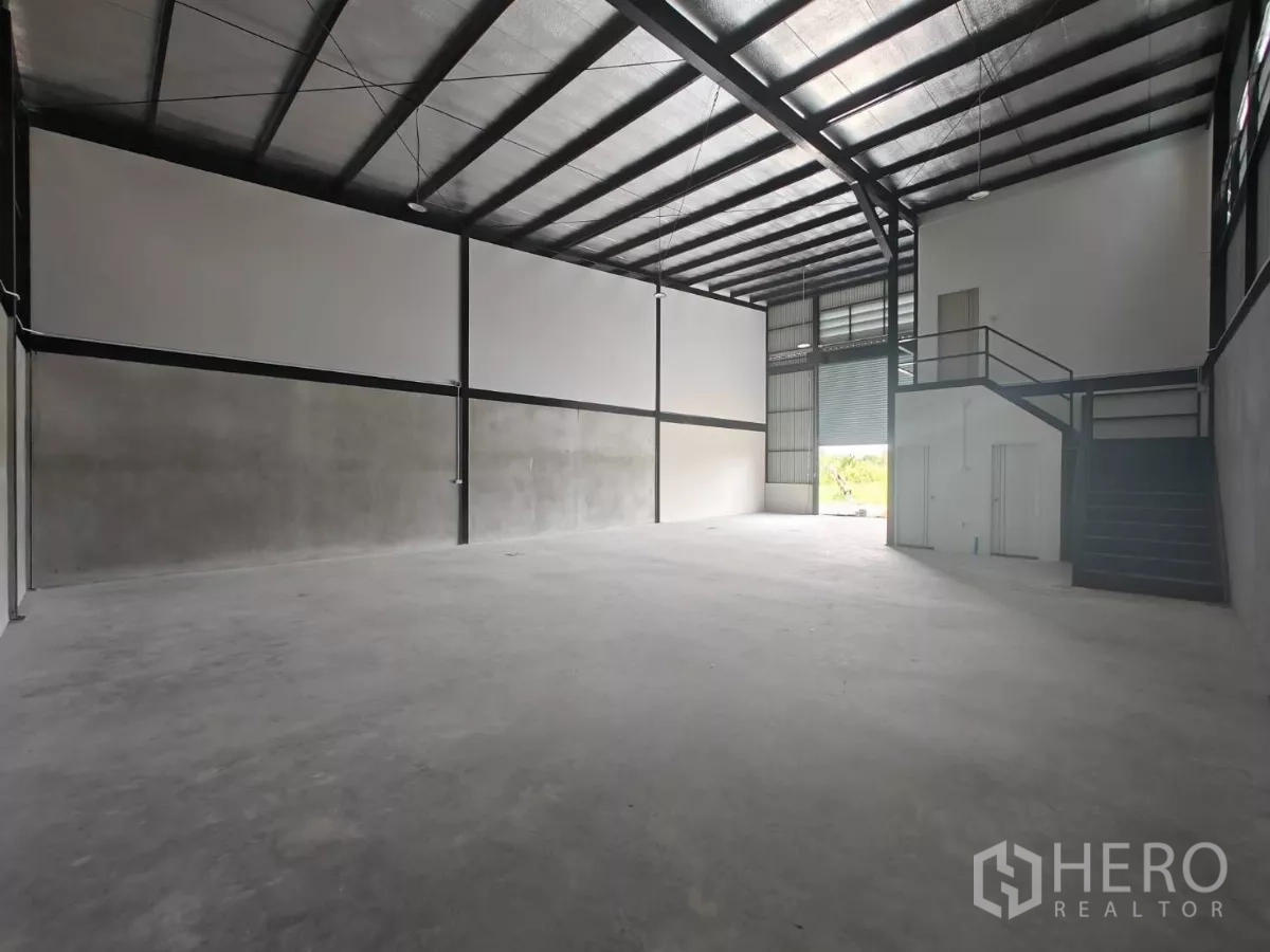 Warehouse for rent in Sam Phran, Nakhon Pathom - Open storage floor with roller shutter entry, mezzanine stair and durable polished concrete.