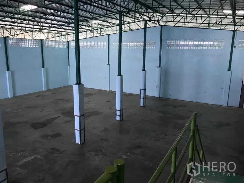 Warehouse for rent in Bang Phli, Samut Prakan - Elevated view of the open warehouse floor with green steel columns and ventilated high walls.