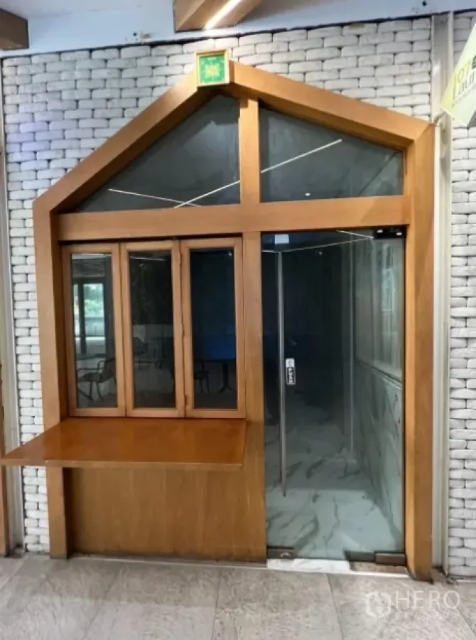 Retail Space for rent in Watthana, Bangkok - Compact retail shopfront with wood frame, glass door and a pass-through counter along an indoor corridor.