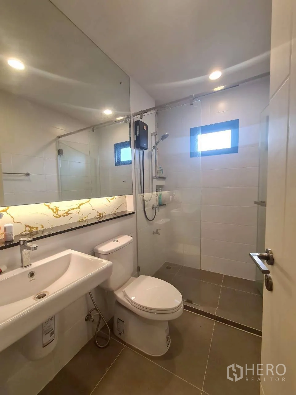 Detached House for rent or sale in Lam Luk Ka, Pathum Thani - Second bathroom with a glass shower enclosure, large mirror and modern fixtures.