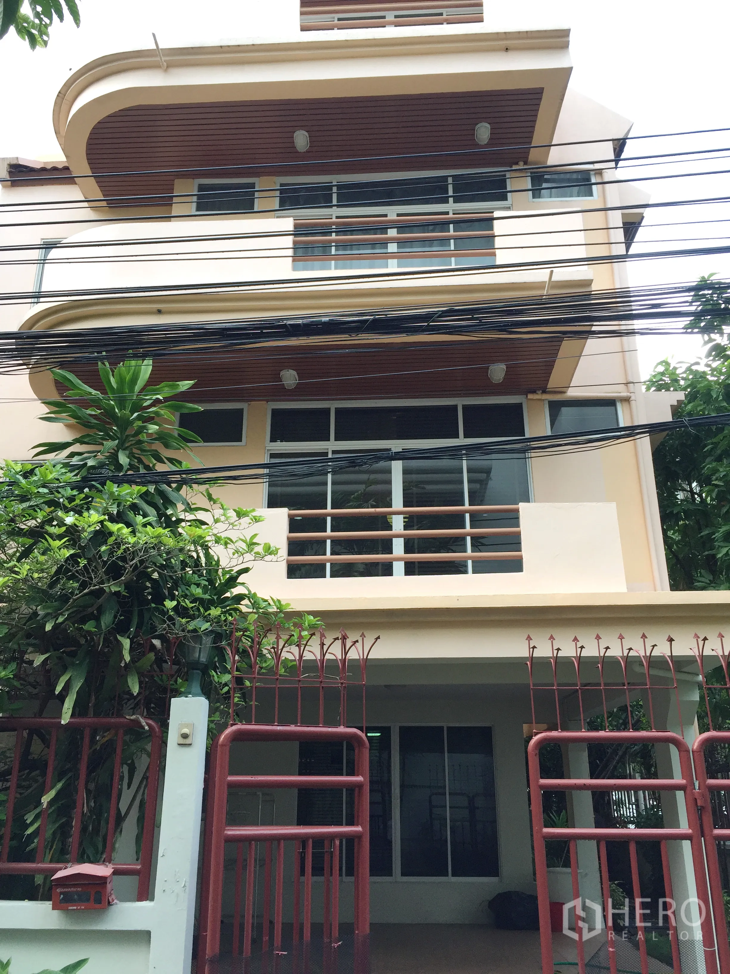 Detached House for rent in Watthana, Bangkok - Multi-storey detached house facade with curved balconies, large windows and a red gated entry.