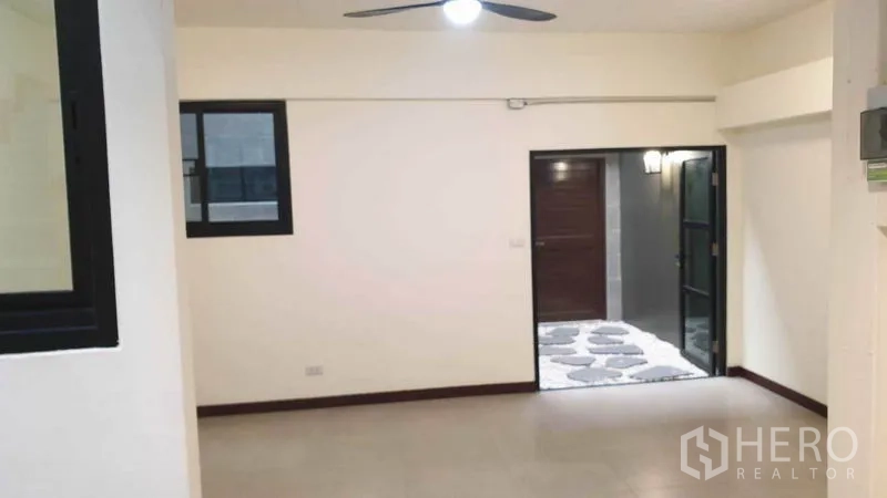 Townhouse for rent or sale in Khlong Toei, Bangkok - Front living area with ceiling fan and doorway to a small courtyard.