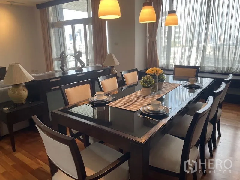 Condominium for rent in Pathum Wan, Bangkok - Eight-seat dining area with pendant lights and city views through large windows.