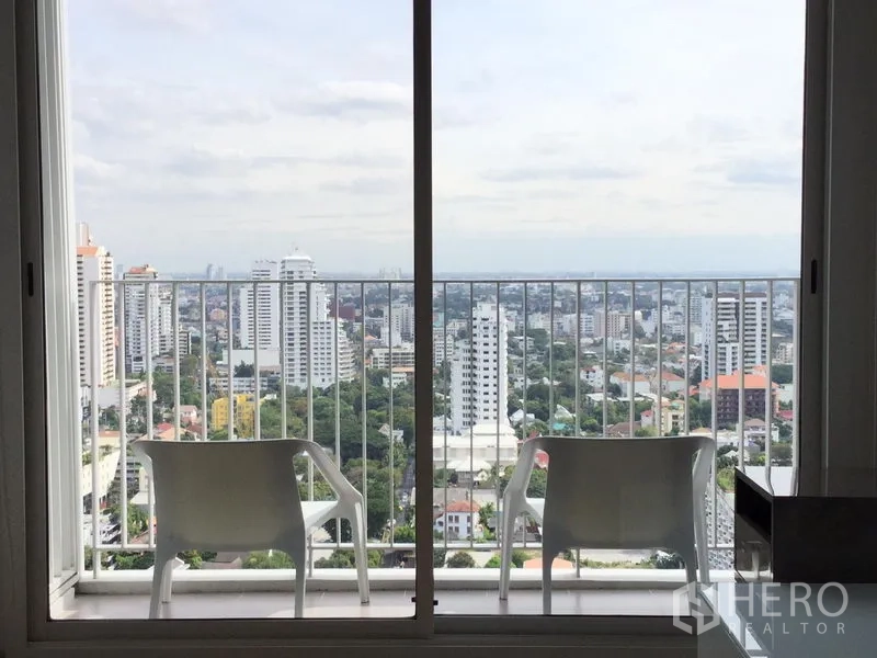 Condominium for rent or sale in Watthana, Bangkok - Balcony with two chairs and a panoramic city view across Watthana district.