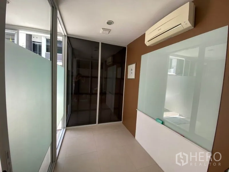 Home Office for rent in Wang Thonglang, Bangkok - Glass-walled corridor room with frosted panels, AC and a mounted whiteboard.