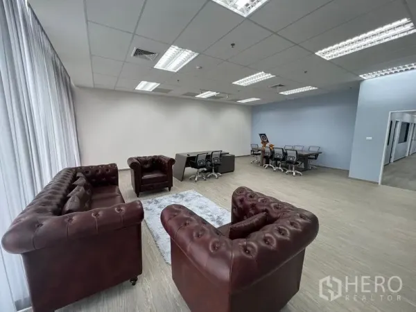 Office Space for rent - Reception lounge with three Chesterfield sofas next to full-height glazing and adjacent workstations.