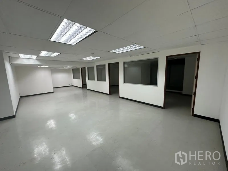 Office Space for rent in Khlong Toei, Bangkok - Open-plan Bangkok office with drop ceiling lights and glass-partitioned rooms.