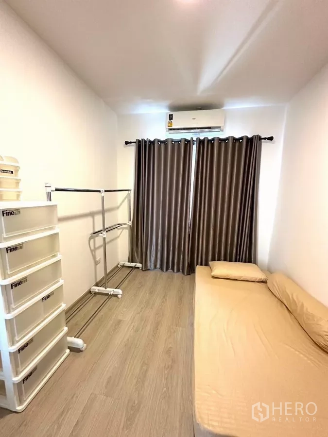 Townhouse for rent in Bang Phli, Samut Prakan - Narrow third bedroom angle with clothes racks and air conditioner.
