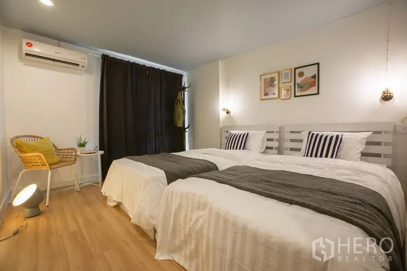 Townhouse for rent in Sathon, Bangkok - Spacious twin bedroom with two single beds, pendant lights, and blackout curtains.
