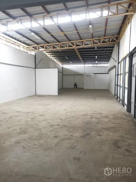 货栈 出租在Suan Luang, Bangkok - 仓库室内高挑空间，金属屋顶带采光带，白墙与混凝土地面。
