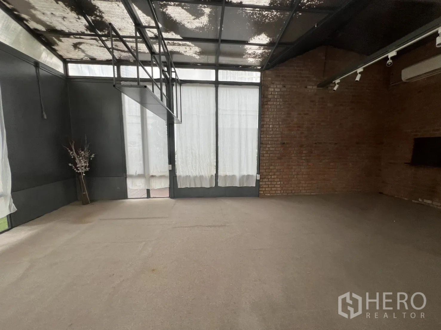 Retail Space for rent in Watthana, Bangkok - Spacious retail floor with exposed ceiling, brick feature wall and doors leading to the outdoor deck.