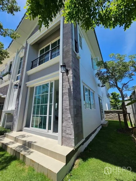 Detached House for rent in Thanyaburi, Pathum Thani - Side facade with sliding glass doors opening to a small private lawn