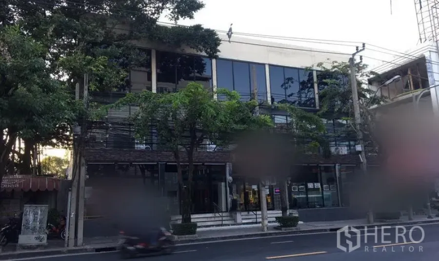 Retail Space for rent in Watthana, Bangkok - Street-facing retail building with wide glass windows and trees along Ekkamai in Bangkok.