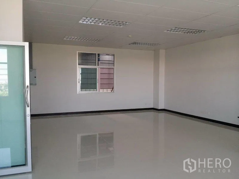 Warehouse for rent in Samut Prakan - Bright office room inside the warehouse with tiled floor, drop ceiling, and fluorescent light fixtures.