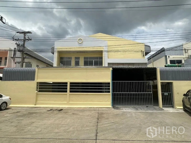 工厂 出租在Pathum Thani - 黄色工厂立面，配安全钢制滑门与前方停车区。