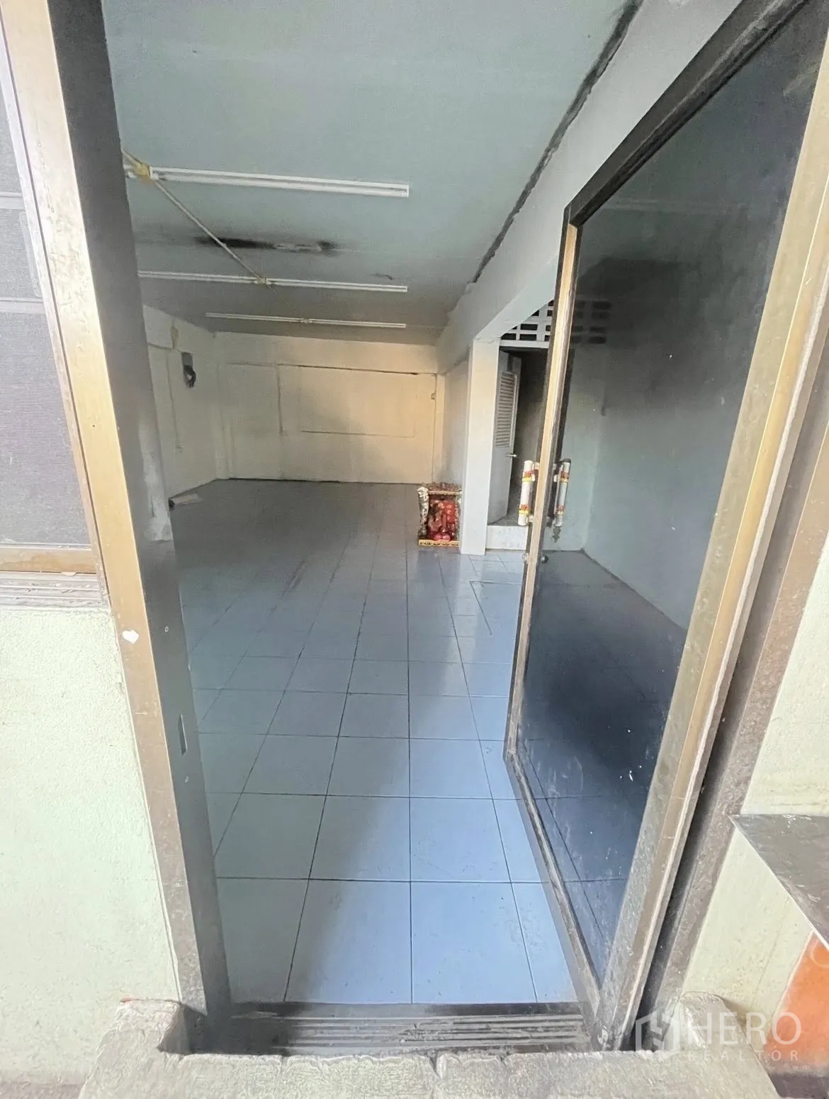 Warehouse for rent in Chatuchak, Bangkok - Tiled multipurpose room viewed from the doorway with overhead fluorescent lights.