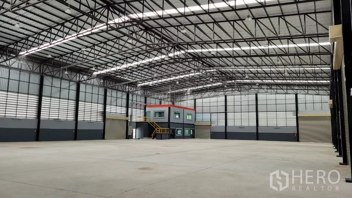 Factory for rent or sale in Phanat Nikhom, Chon Buri - Bright warehouse hall with several loading doors and mezzanine-style office block.