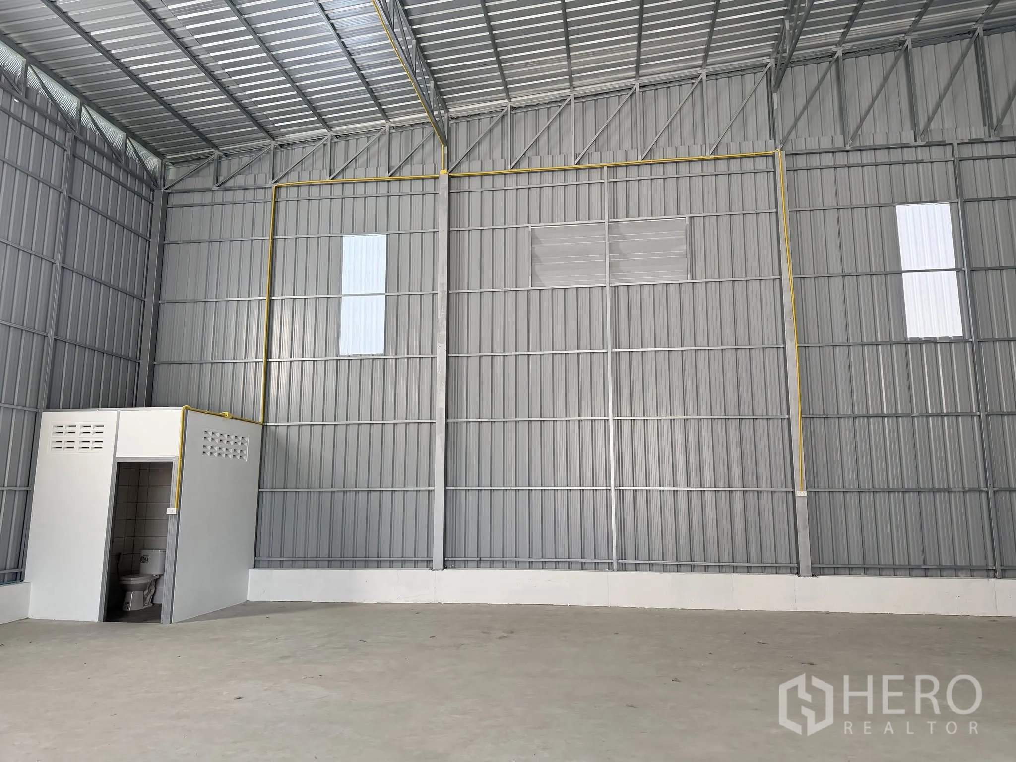 仓库 for rent in Bang Kapi, Bangkok - 仓库内部，金属覆面、层高较高的屋顶，混凝土地面，带内置卫生间。