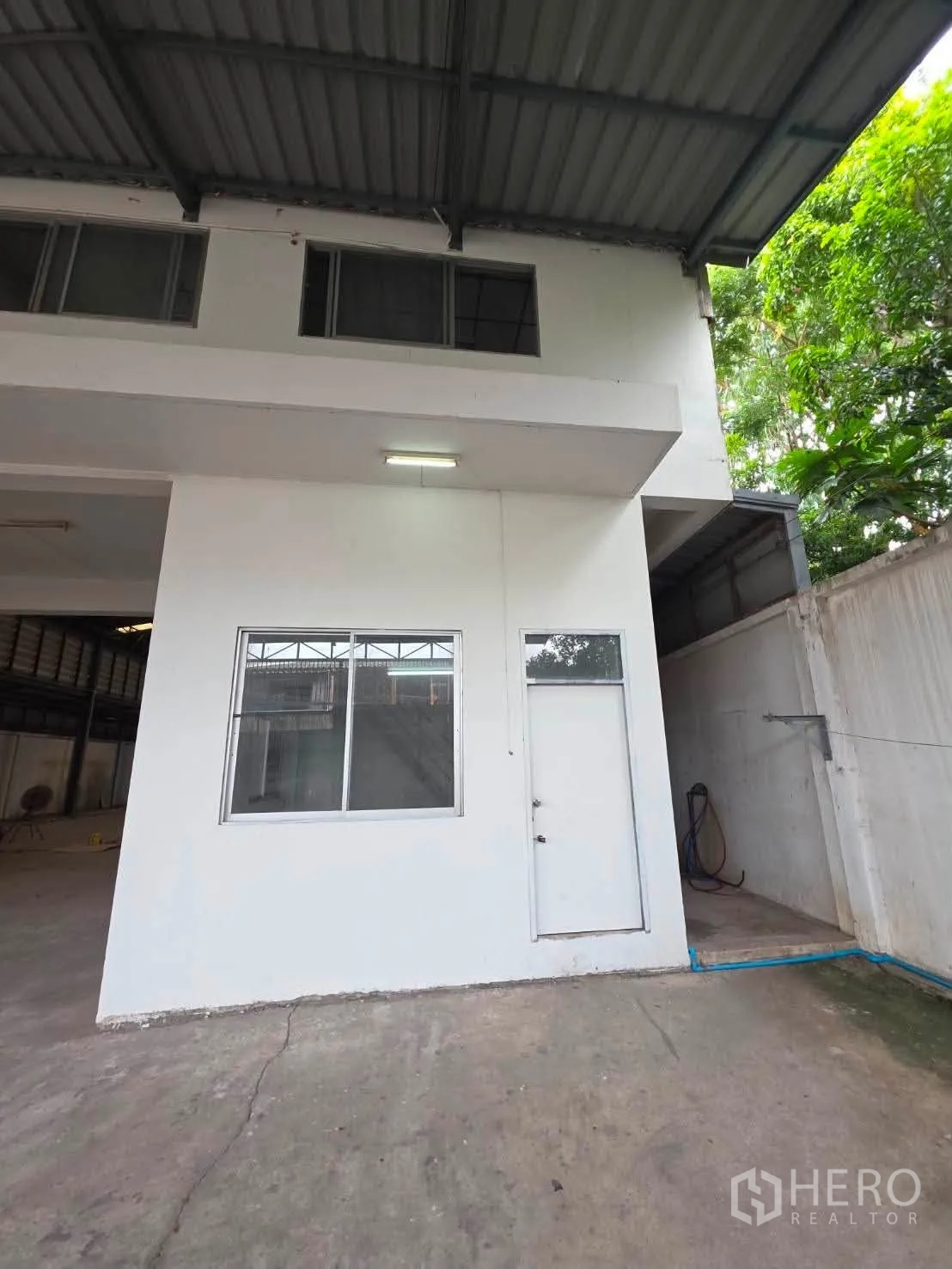 Warehouse for rent or sale in Phra Khanong, Bangkok - Side of the office block under roof with window and nearby greenery.