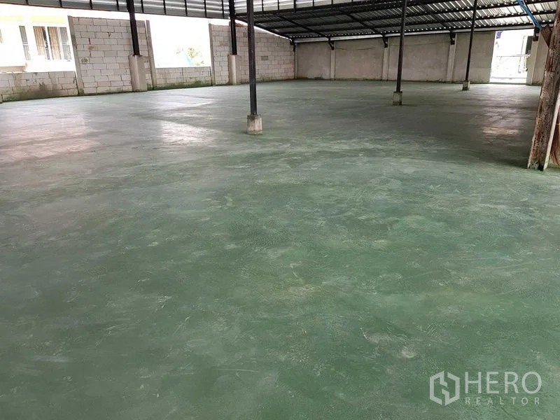 Warehouse for sale in Lam Luk Ka, Pathum Thani - Spacious covered hall with green epoxy concrete floor and high roof structure.