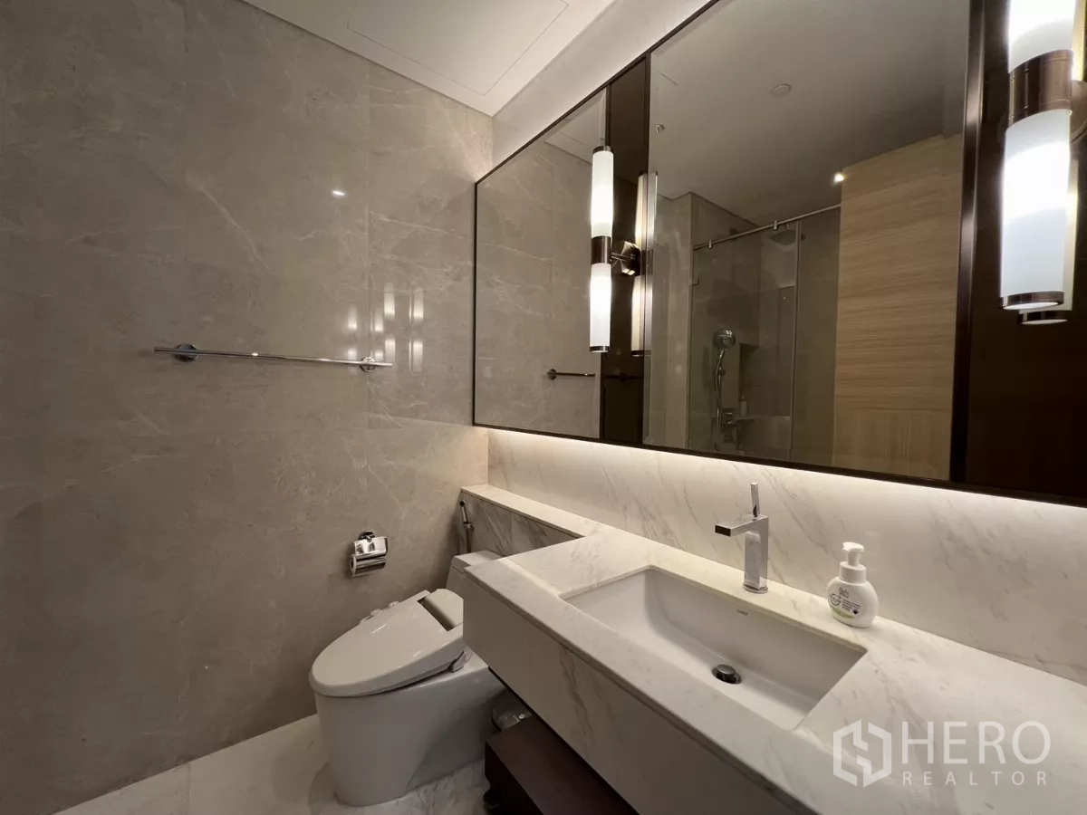 Condominium for rent in Pathum Wan, Bangkok - Marble bathroom with long vanity, large mirror and smart toilet.
