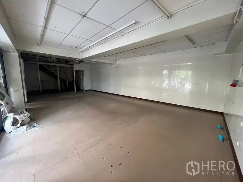 店屋 出租在Watthana, Bangkok - 一层零售开间，白色墙面与日光灯照明。