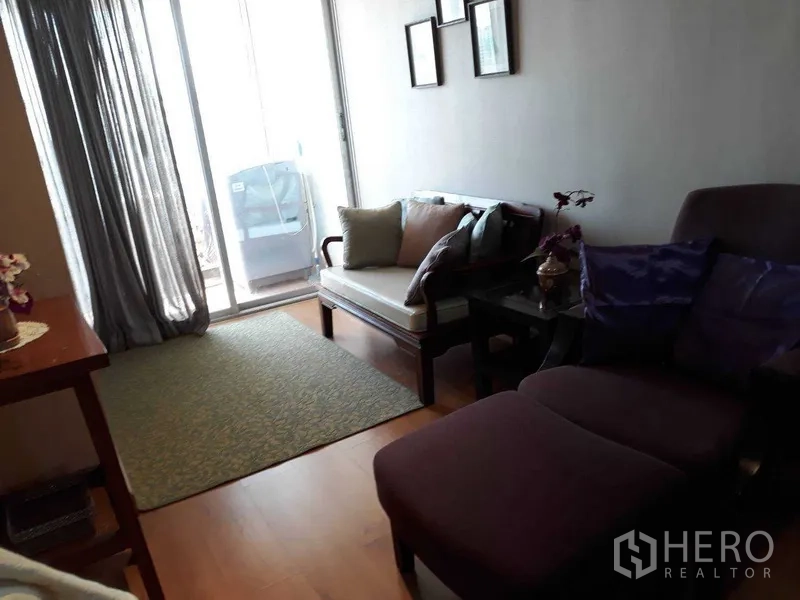 Condominium for rent or sale in Khlong Toei, Bangkok - Bright living room with sofa set and chaise lounge beside sliding glass doors opening to the balcony.