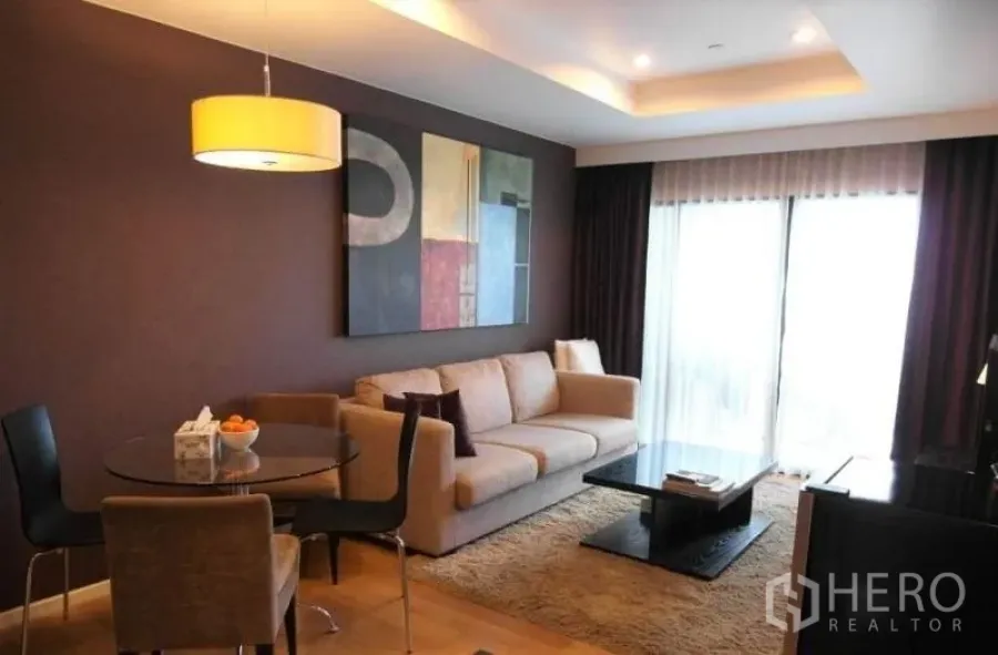 Condominium for rent in Sathon, Bangkok - Another view of the open‑plan living room with sofa, rug, coffee table and balcony doors.