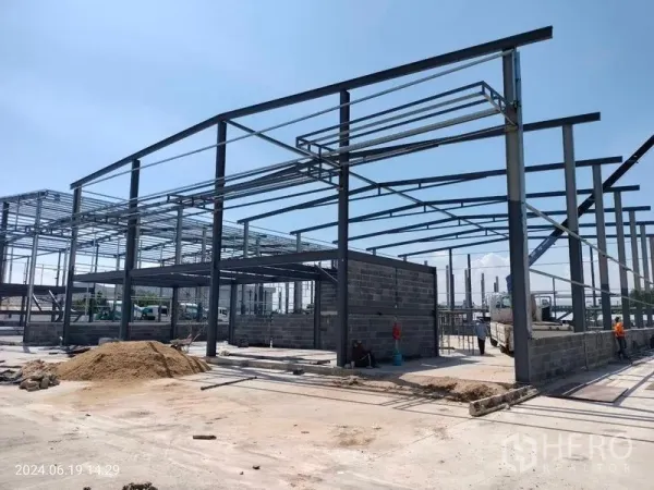 Warehouse for rent in Samut Prakan - New-build warehouse in Bang Phli under construction showing a high steel frame, block walls, and a wide concrete yard.