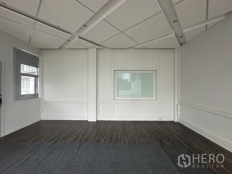 Retail Space for rent in Bang Rak, Bangkok - Interior room with white paneled walls, dark wood flooring, and acoustic ceiling panels.