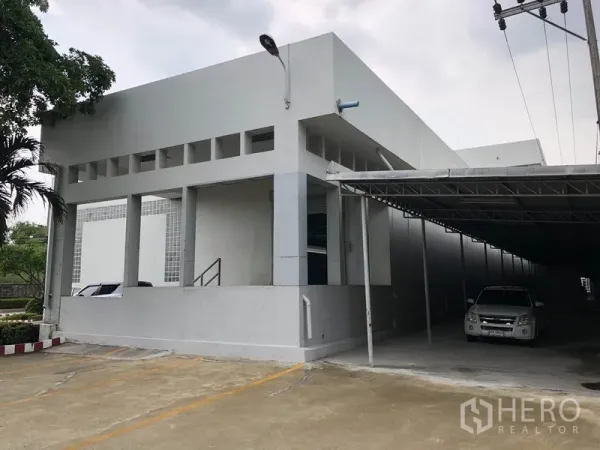 Factory for rent in Lat Krabang, Bangkok - Corner view of the building with covered parking and a roller shutter entry.