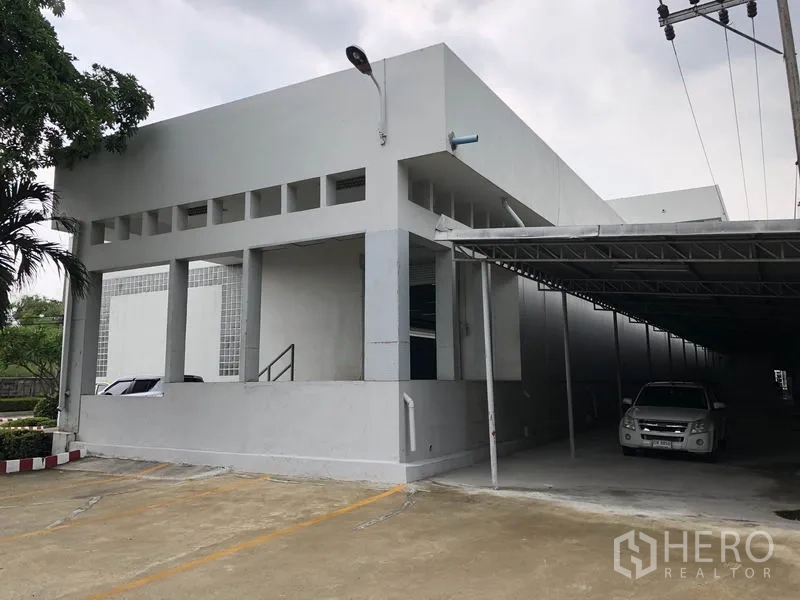 Factory for rent in Lat Krabang, Bangkok - Corner view of the building with covered parking and a roller shutter entry.