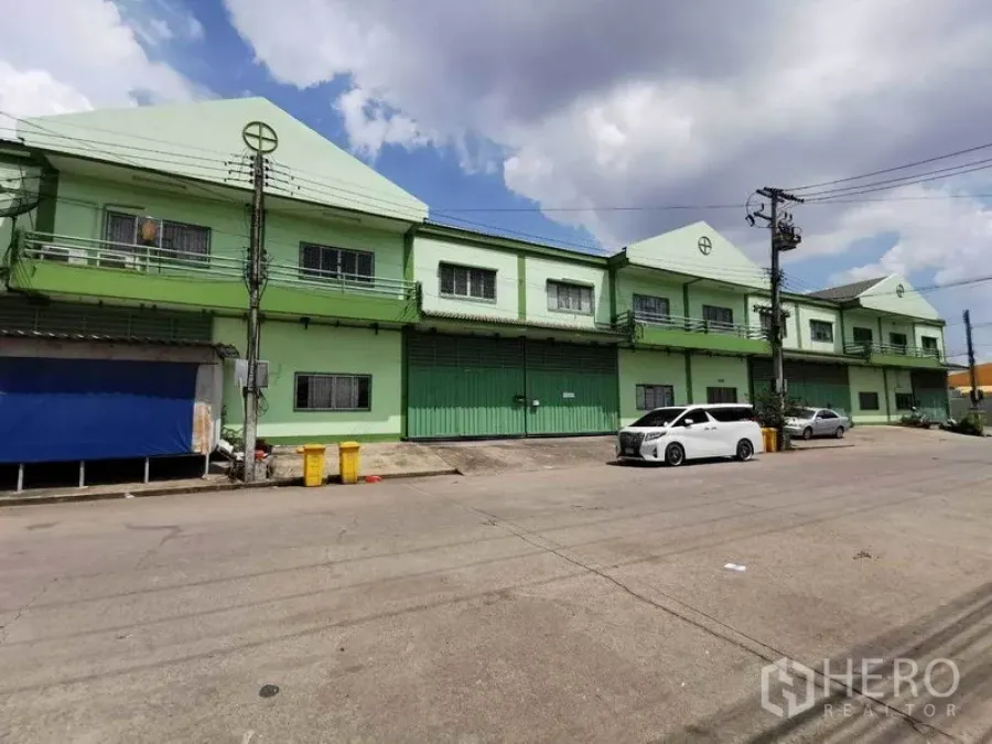 工厂 出租在Samut Sakhon - 成排绿色工厂沿宽阔道路分布，设停车位与电线杆。
