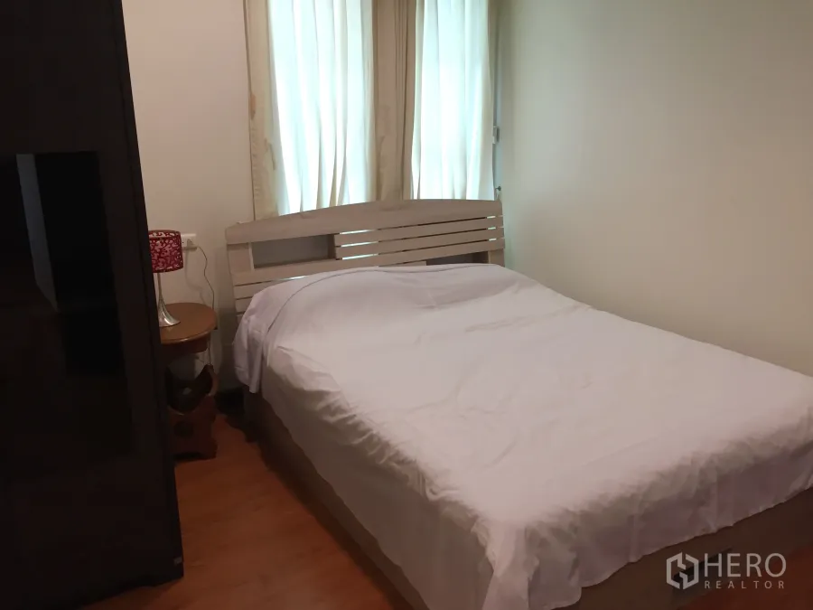 Condominium for rent in Khlong Toei, Bangkok - Bright bedroom with white bedding, wood floor and sheer curtains in a Sukhumvit condo.