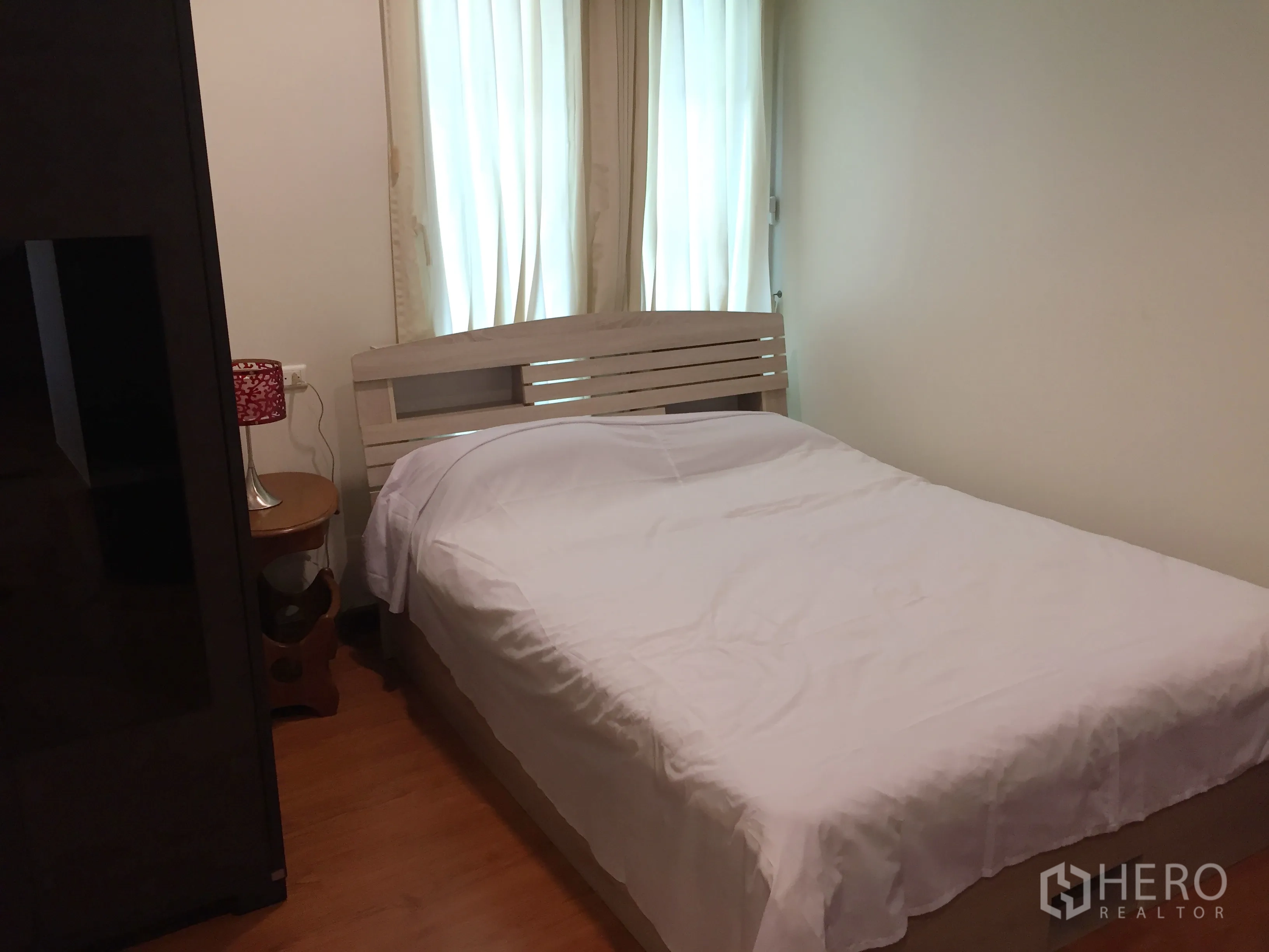 Condominium for rent in Khlong Toei, Bangkok - Bright bedroom with white bedding, wood floor and sheer curtains in a Sukhumvit condo.