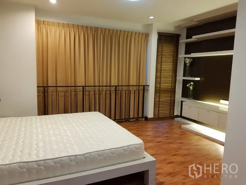 Townhouse for rent in Phra Khanong, Bangkok - Spacious master bedroom with wood floors, floor-to-ceiling curtains and built-in shelves.