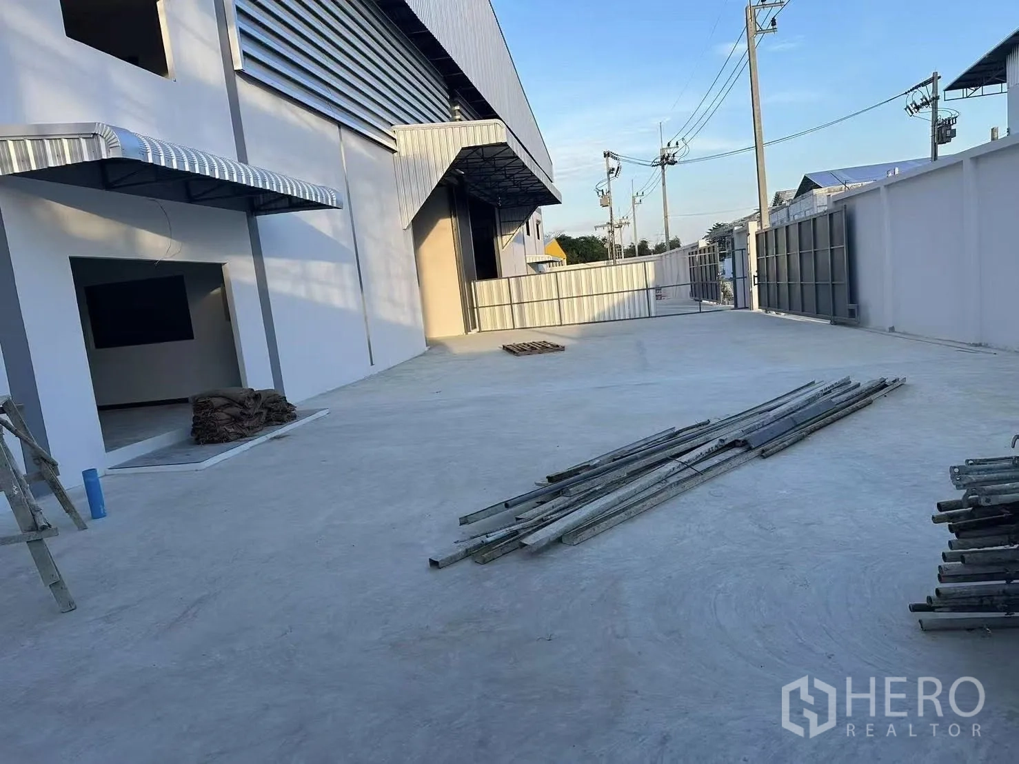 Factory for rent in Nong Khaem, Bangkok - Expansive front loading yard with concrete apron, canopies and sliding gate for truck access.