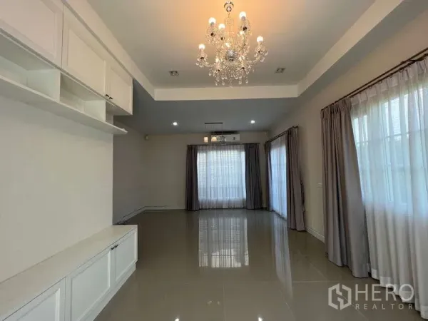 独立式住宅 出租或出售在Khan Na Yao, Bangkok - 明亮客厅，水晶吊灯、亮面地砖与落地窗帘。
