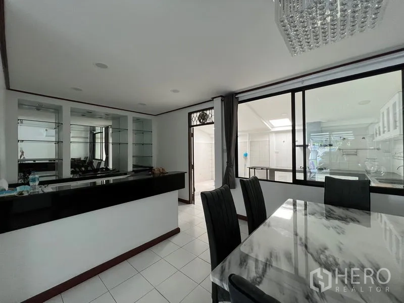 Townhouse for rent in Din Daeng, Bangkok - Dining area with marble-top table, glass bar counter and sliding glass partition.