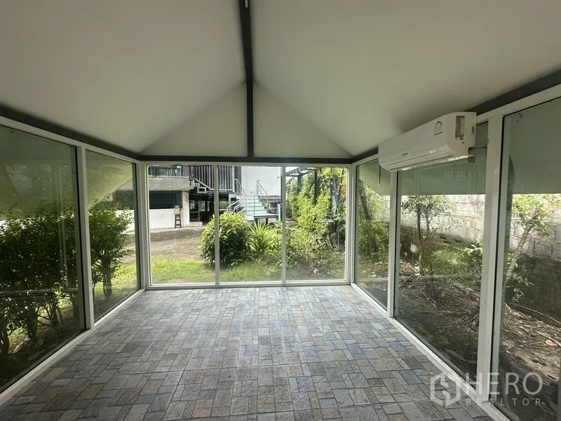 Standalone for rent in Prawet, Bangkok - Interior of a glass pavilion with air conditioner and garden views.