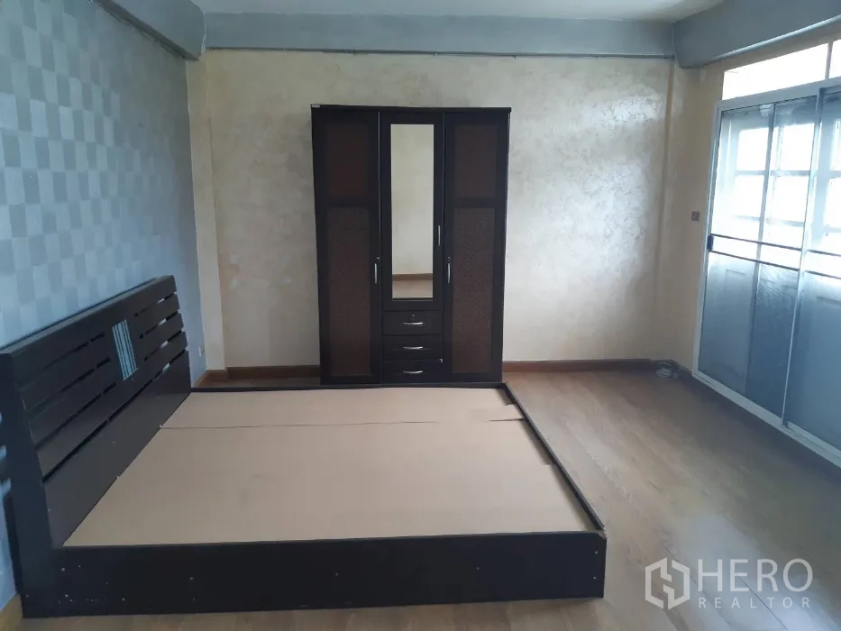 Townhouse for rent in Khlong Toei, Bangkok - Bedroom with dark wood platform bed frame, wardrobe and wood‑look flooring.