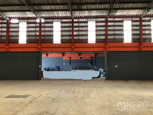 Factory for rent in Phra Pradaeng, Samut Prakan - Interior showing ventilated louver windows, bright orange beams, and open work area.