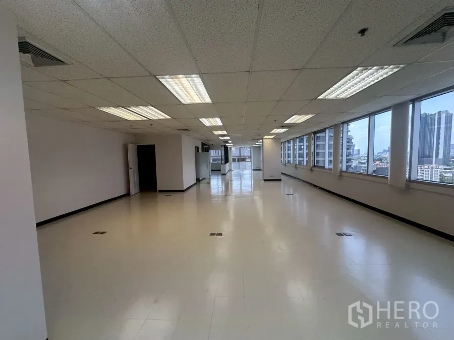 Office Space for rent - Long open workspace with a window wall bringing in daylight and city skyline views.