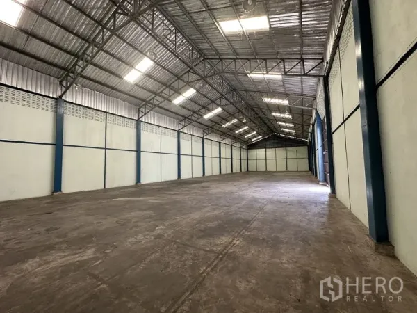 Warehouse for rent in Phra Nakhon Si Ayutthaya - Long clear-span storage hall with insulated roofing, bright lighting, and a wide sliding door entry.